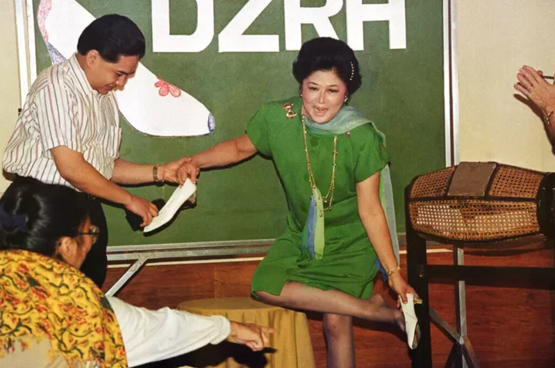 伊美黛從腳上脫下一雙綴有珍珠的白鞋，親手贈予猜中她於1991年11月4日結束流亡返菲的幸運兒。圖／美聯社