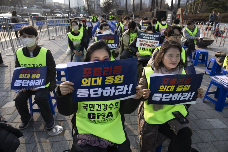 參與罷工行動的醫師舉著寫有「停止民粹醫療政策」的標語牌，在首爾總統府附近抗議。（圖／歐新社）