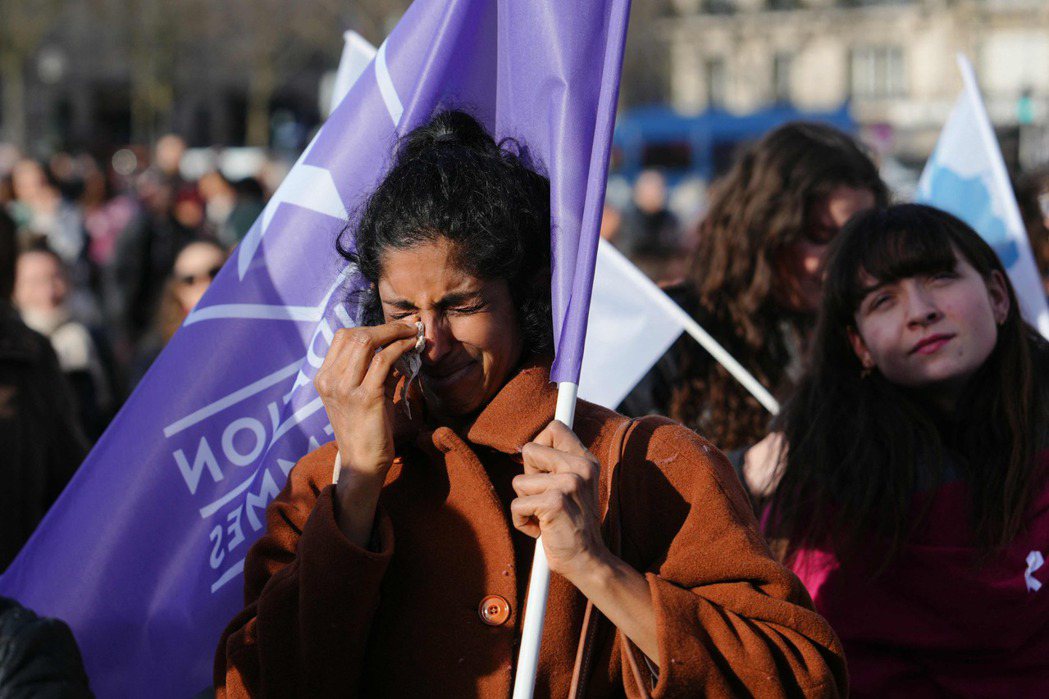 手持法國婦女基金會旗幟的遊行示威者。 圖／法新社