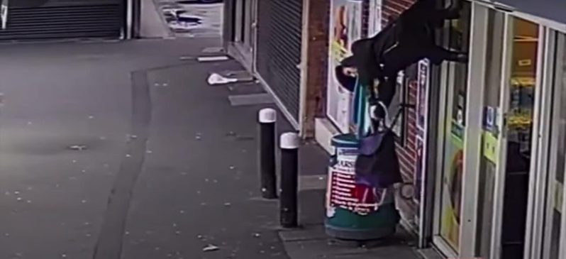 英國71歲阿嬤休斯（Anne Hughes）日前在一家商店等開門時，遭到升起的鐵捲門夾住外套，整個人如「倒掛金鉤」般被懸在半空中。取自YouTube
