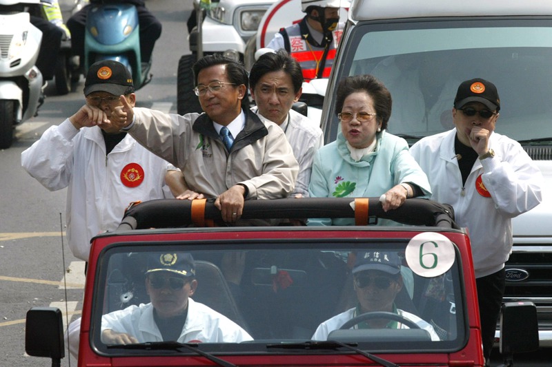前總統陳水扁2004年3月19日在台南選舉掃街時遭人槍擊，陳水扁遭槍擊後苦撐揮手，隨扈自後方撐住他的身體，副總統呂秀蓮也有槍傷，兩邊國安局人員正以無線電通報情況。圖／聯合報系資料照片
