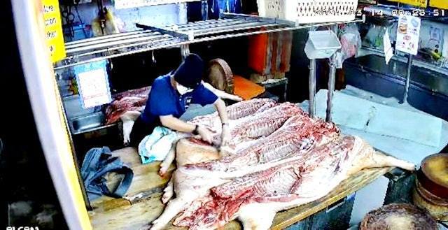 馬來西亞檳城發生豬肉偷竊事件，1名大媽深夜潛入肉檔偷偷切走豬肉。（閉路電視截圖）