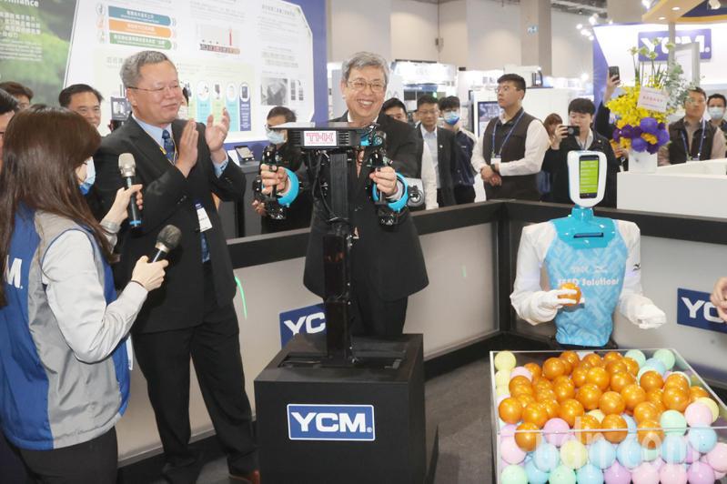 行政院長陳建仁（中）上午出席台灣國際工具機展，陳建仁操作 YCM X THK 聯合展示的「SEED」機器人成功抓起一顆球，一旁的永進機械董事長陳伯洋（左二）拍手鼓掌。記者蘇健忠／攝影