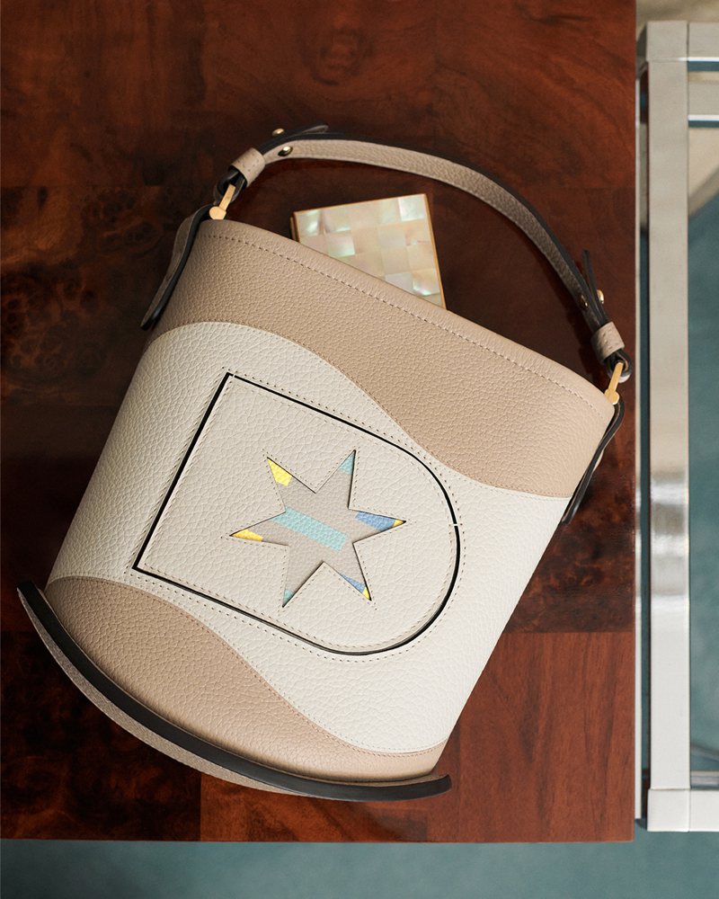 混用季风褐与象牙白色彩的Pin Mini Bucket Oriflamme包款，10万9,300元。图／Delavux提供