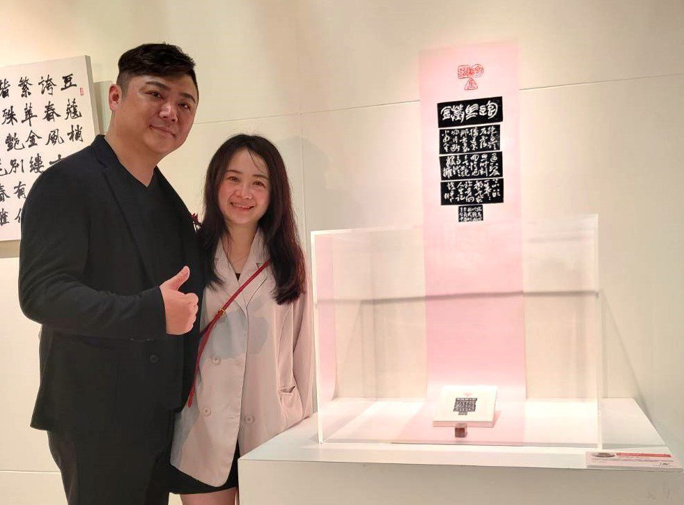 第16屆篆刻組首獎古員齊與妻子呂珮菱在得獎作品旁合影。圖片提供／古員齊