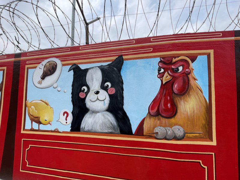 新竹市空军基地旁靠成功路围墙最近完成一大片彩绘，画上以12生肖动物搭铁路小火车的童趣模样，有「中正路的那只狗」之称的「令狗」也在上头。记者张裕珍／摄影