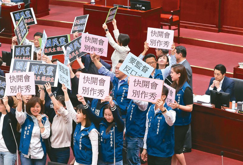 台北市長蔣萬安（右）昨赴議會施政報告，民進黨議員拿出字牌高喊「國民黨棄民主、顧幼主」；國民黨議員反擊舉「快開會、別作秀」，雙方吵成一團，坐在備詢席的蔣萬安面無表情。記者胡經周／攝影