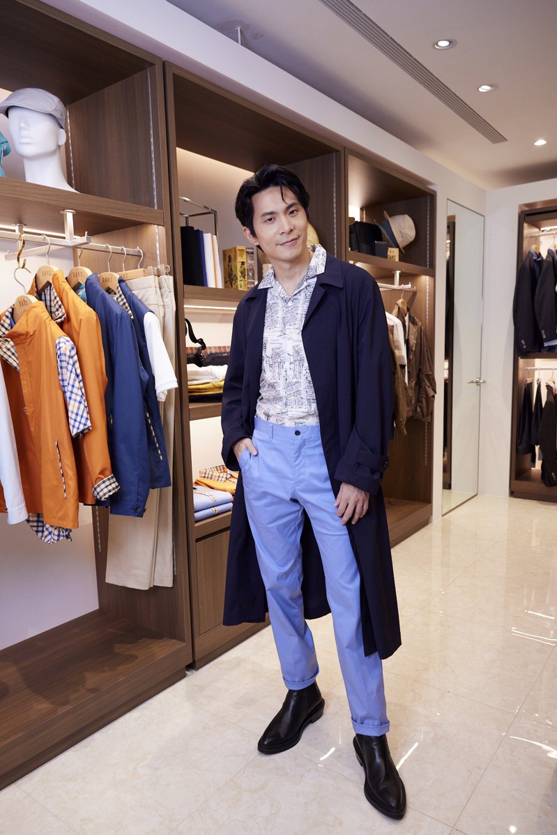 姚淳耀身穿长版风衣内搭DAKS联名华裔插画家Slowboy限定T恤，以及水蓝色长裤。图／DAKS提供