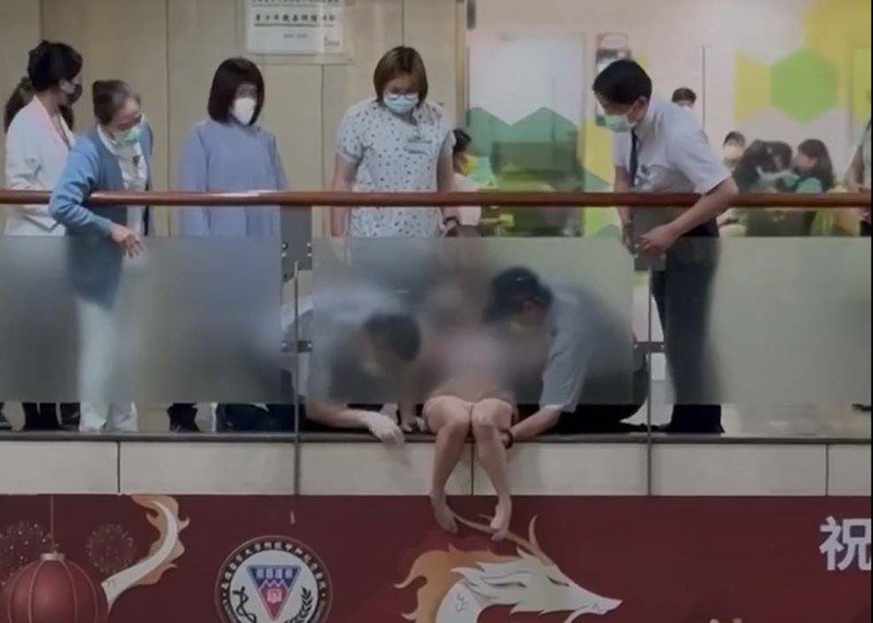 一名女子在高医候诊时不慎滑落玻璃墙外，双腿被玻璃墙卡住，一旁民众及保全、医疗人员协助脱困。图／撷取自记者爆料网