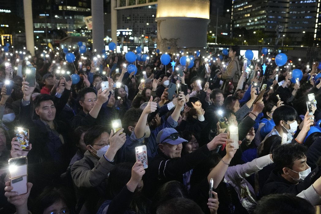 共同民主黨支持者9日在大選前最後的造勢晚會上，揮舞手機閃光燈。 圖／美聯社