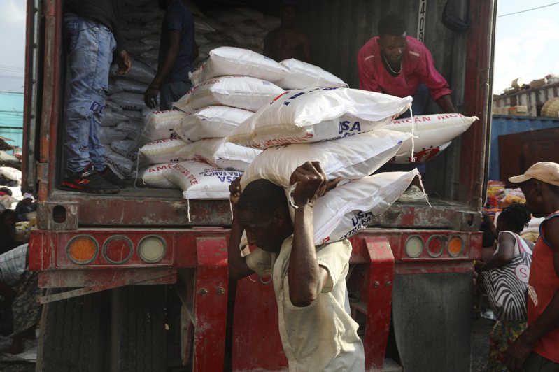圖為海地太子港一名工人在貨車上卸下一袋袋大米。 美聯社