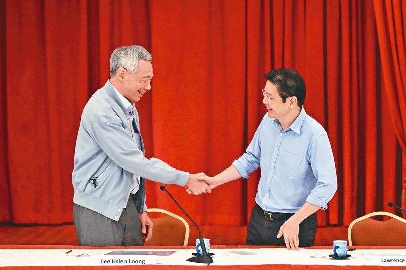 新加坡總理李顯龍（左）2022年在一場記者會後與財長黃循財（右）握手。李顯龍15日宣布將卸任，由副總理黃循財接任總理。（路透）