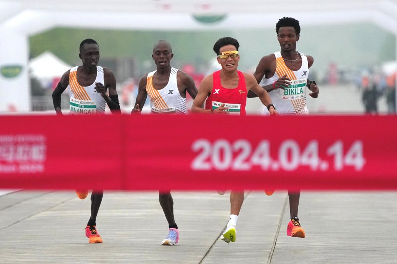 北京14日舉行半程馬拉松爆出跑假賽爭議，3名領先非洲選手最後關頭疑似護送何杰（右二）率先衝線，遭網友諷刺半馬變「伴馬」，事後一名非洲選手受訪自招只是陪跑員。路透