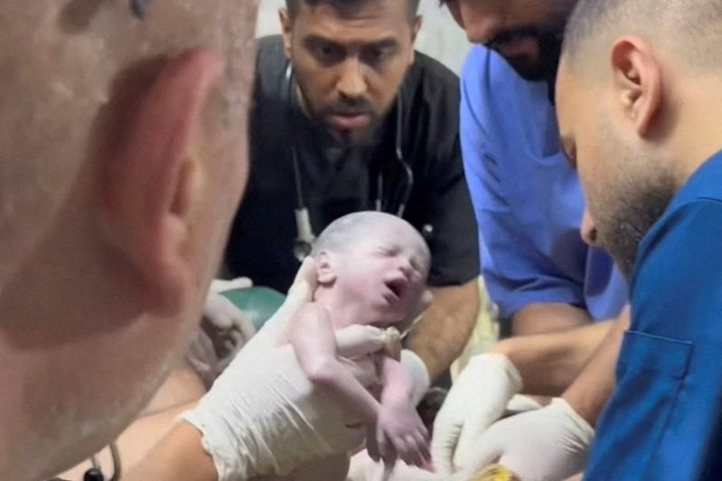 圖為醫護人員從死亡的巴勒斯坦婦女子宮中接生一名女嬰。 路透