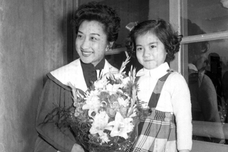 1955年4月24日，應邀拍攝「聖女媽祖傳」擔任女主角的影星周曼華（左），由香港飛抵台北，在機場接受在媽祖片中飾演幼年時期媽祖的張小燕（右）獻花。圖／聯合報系資料照片