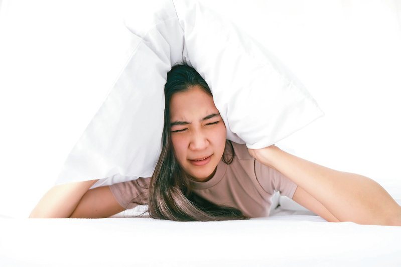 睡覺時被地震震醒，應先躺在床上「用枕頭保護頭部」。圖／123RF