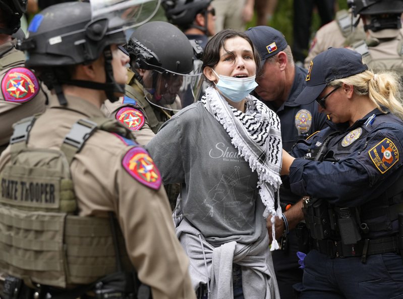 美國德州大學奧斯汀分校24日傳出示威學生和大批警力爆發肢體衝突，當局證實至少20人被逮捕。圖可見現場一名女性遭警方制伏逮捕。美聯社