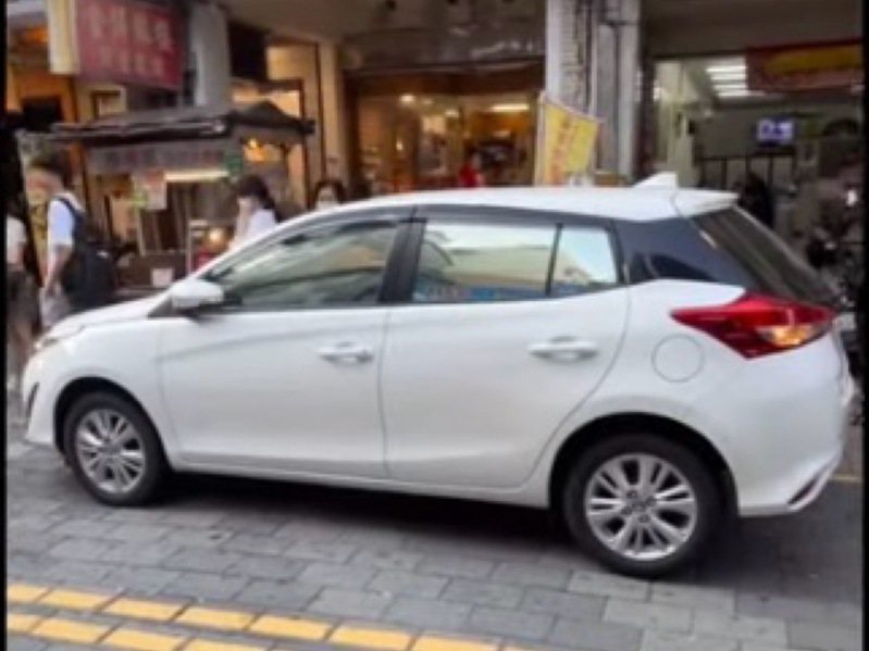 台南市警二分局指出，白色轿车未能紧靠路旁，违规临时停车致影响妨碍他车通行部分，已违反道路交通管理处罚条例第55条，将处300元以上600元以下罚锾。图／读者提供