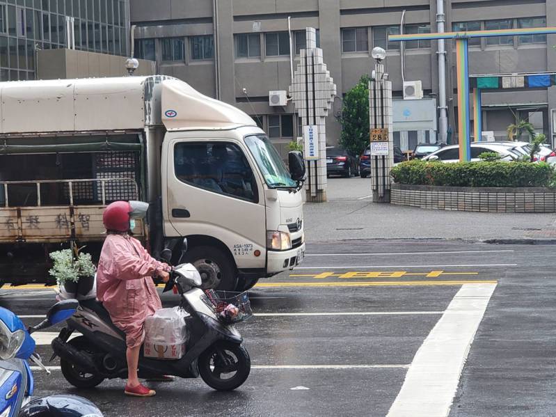 機車騎士今天中午12時許，身穿雨衣在高市三民區大昌路停等紅燈。記者王勇超／攝影
