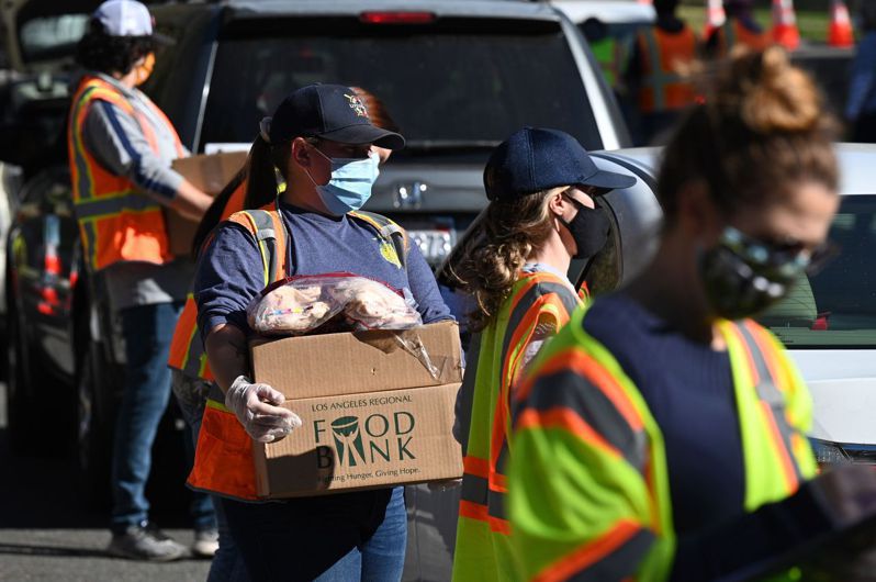 疫情大流行期间，很多穷人生活潦倒，要依靠政府的救济食物生活；图为在洛杉矶，食物银行的员工在派发免费食物。(Getty Images)(photo:UDN)