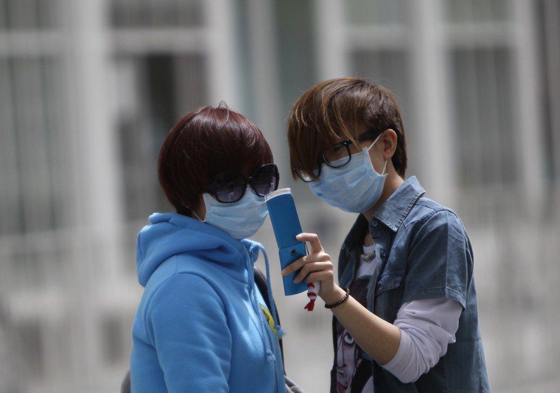 圖為在北京街頭，兩名青年在看智能手機。(路透資料照片)
