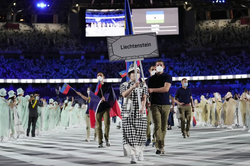 東京奧運會開幕式上，出場隊伍前頭寫著國家名稱的標語牌以漫畫對話框作為造型，舉牌員的穿著也加入漫畫風格的巧思；圖為列支敦士登代表隊。(美聯社)