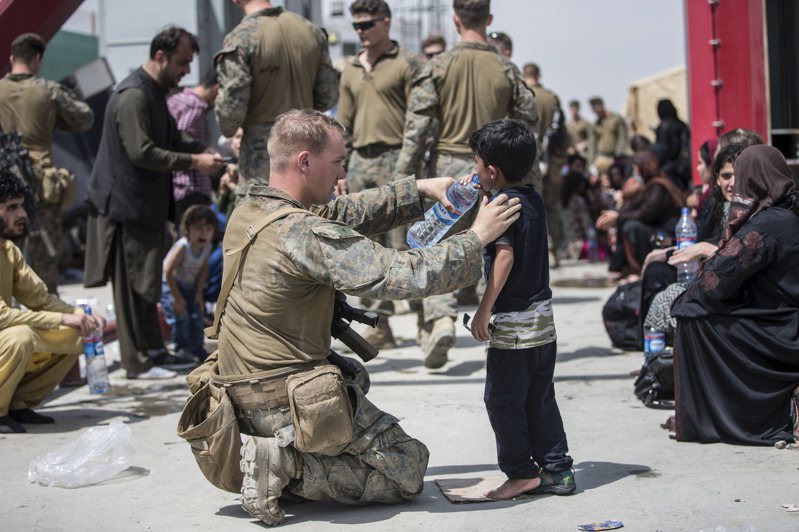 成千上万上的阿富汗平民20日围在机场，千方百计要搭机逃离阿富汗。图为20日驻守喀布尔国际机场的美军特种部队正在分发清水给等候撤离的阿富汗儿童。(美联社)(photo:UDN)