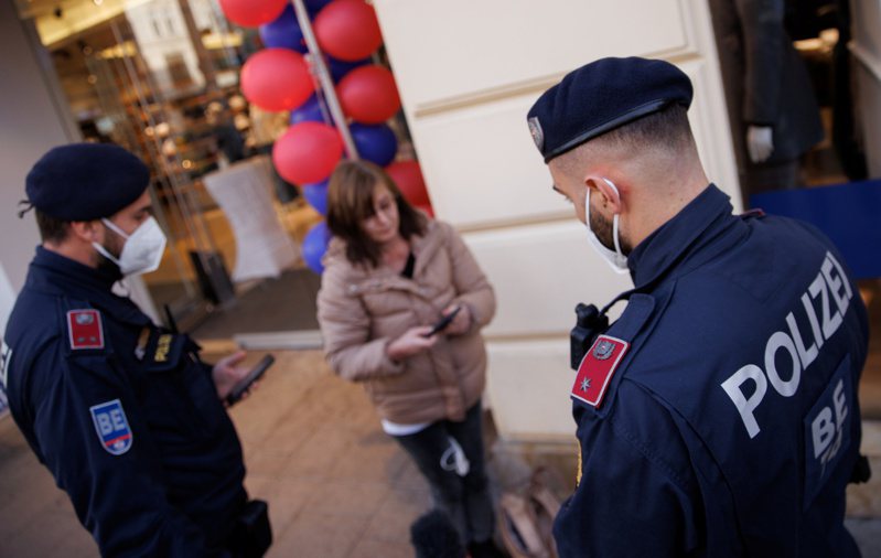 奧地利警方在一間商店門口檢視民眾的接種證明。 （路透）