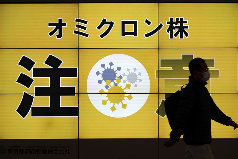 日本東京一名戴口罩男子13日經過呼籲民眾注意Omicron變異株的告示。美聯社