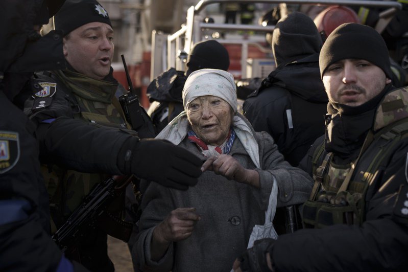 俄军15日狂轰乌克兰首都基辅，一位妇女自被击中的住家公寓大楼中逃出，惊魂甫定，被警察与消防员救护。(美联社)(photo:UDN)