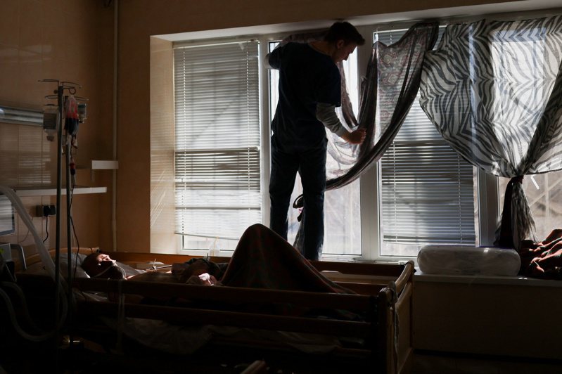 尼古拉耶夫一名护理人员在窗户上拉一张床单挡住阳光，一名受伤的乌克兰士兵躺在病床上。路透(photo:UDN)