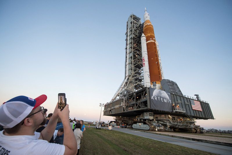 NASA計畫重返月球，強大的新型火箭已經推上佛州卡拉維爾角的發射架。遊客忙著拍攝登月火箭的英姿。(路透)