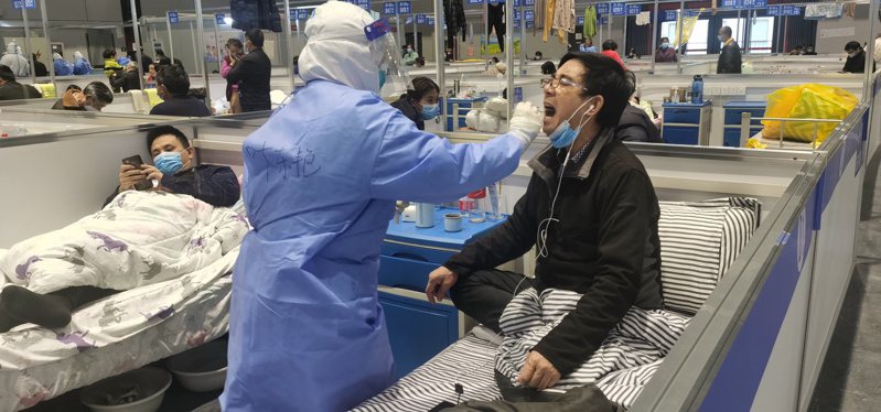 上海封控多日，圖為方艙醫院的醫護人員正為收容者取樣。(歐新社)
