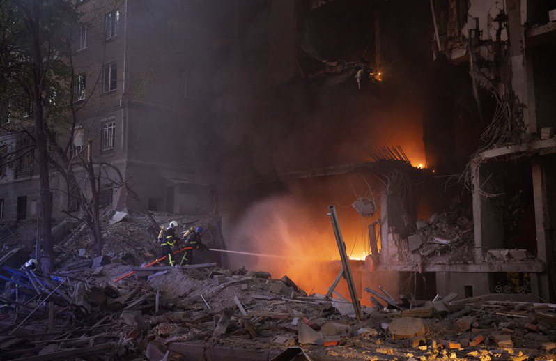 俄軍砲彈擊中基輔的一座建築後，消防人員正在滅火。(美聯社)