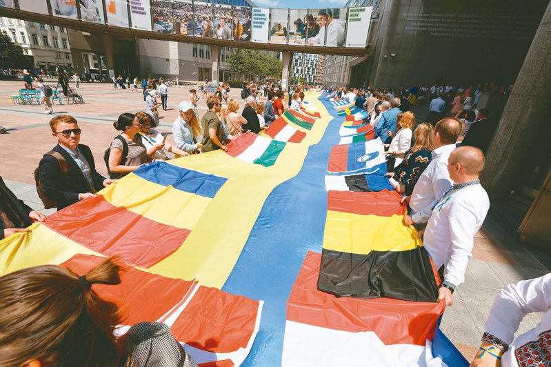 國旗大拼圖 挺烏入歐盟 
歐盟峰會23日討論烏克蘭候選國資格當天，歐洲議會議員和烏克蘭代表在歐洲議會外展開30公尺長的歐盟各國與烏克蘭國旗造勢。（路透）