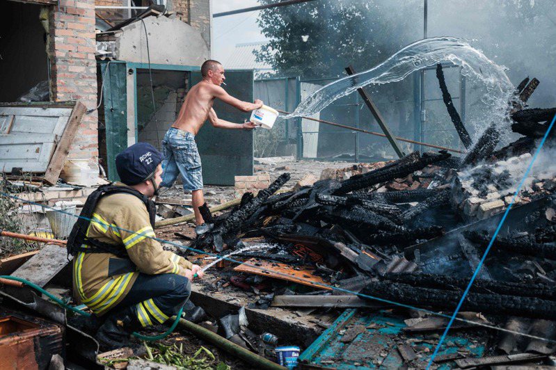 在俄罗斯入侵乌克兰期间，巴赫穆特镇19日发生空袭后，当地居民帮助消防员扑灭了一座房屋院子里的大火。（Getty Images）(photo:UDN)