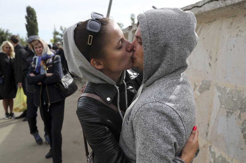 一名俄羅斯新兵24日在俄羅斯伏爾加格勒的一個徵兵中心外擁抱和親吻他的妻子。（美聯社）