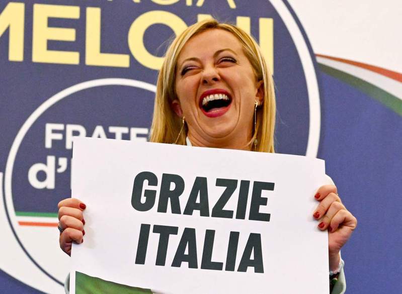 義大利大選，「義大利兄弟黨」黨魁梅洛尼成為首位女性總理。圖為梅洛尼26日上午宣布勝選後，手持「謝謝，義大利」標語，向支持者致意。(美聯社)