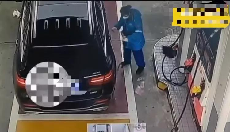 在加油工收取加油費時，一雙手從奔馳車後排將數百元從窗戶遞出，錢落在地上。（視頻截圖）