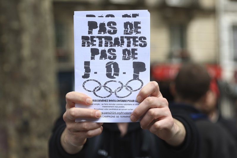 法國民眾不滿總統馬克宏強行通過年金改革，醞釀癱瘓2024巴黎奧運。圖為民眾手中拿著「不撤銷就沒奧運」標語。（美聯社）