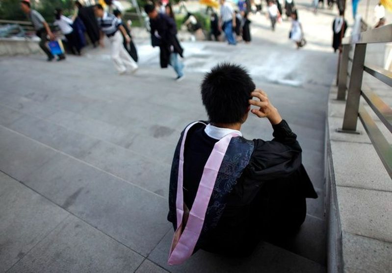 中國近期大幅上調大學學費，部分院校的學費更是20年以來首次上調。圖為上海復旦大學一名畢業生坐在校園外等待參加畢業典禮。(路透)