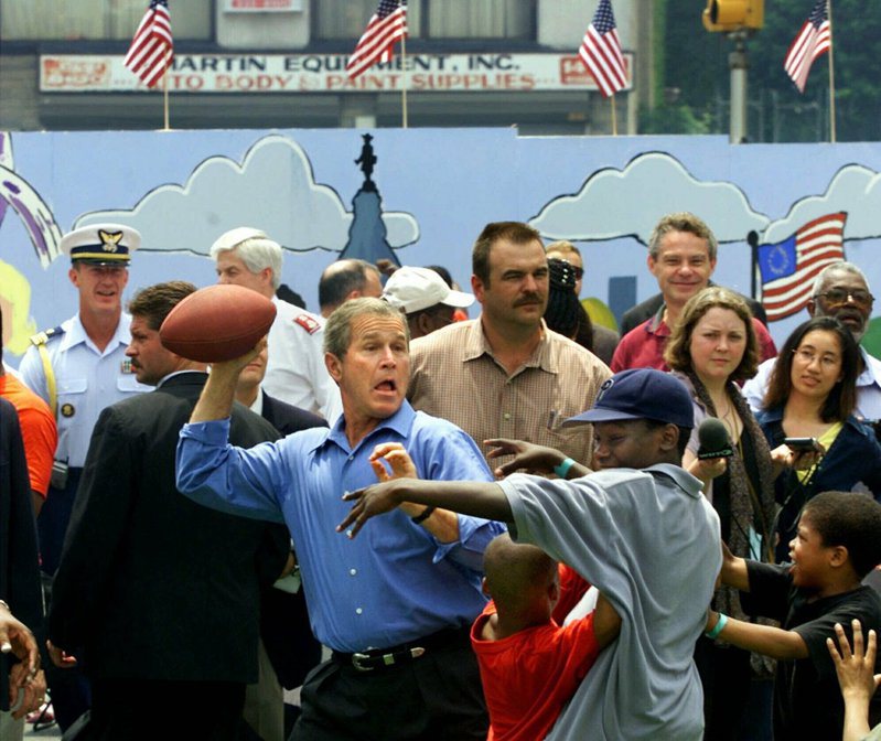 小布希總統2001年國慶日在費城與孩童在街坊派對拋擲足球。(美聯社)