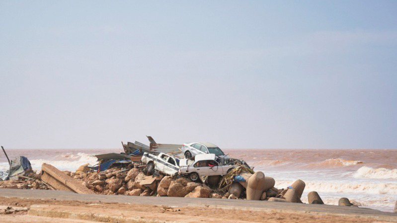 利比亞德納海濱堆滿被洪水沖到海岸的汽車與建物殘骸、遺體。（美聯社）
