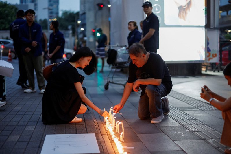 泰國曼谷暹羅百麗宮發生槍擊死傷慘案，遊客在購物中心外點燃蠟燭悼念。（路透）