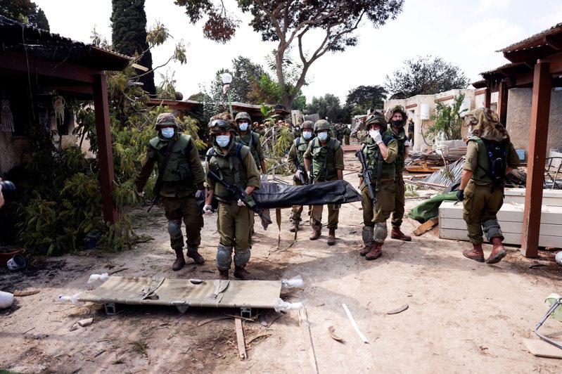 以色列軍方進入以國南部社區卡法阿扎（Kfar Aza），搬運罹難者屍體。（路透）