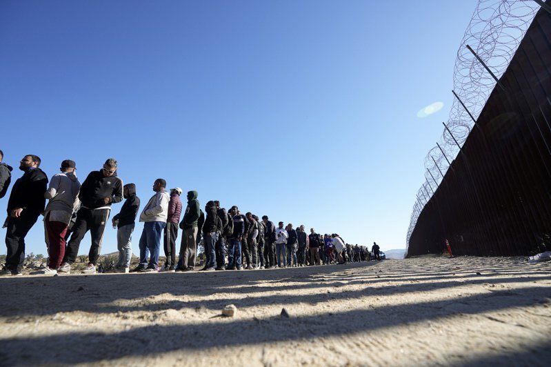 不同立場的選民都希望拜登總統能拿出辦法，遏制無證移民氾濫現象。圖為無證移民今年10月間在邊界圍牆邊排隊，準備進入美國。(美聯社)