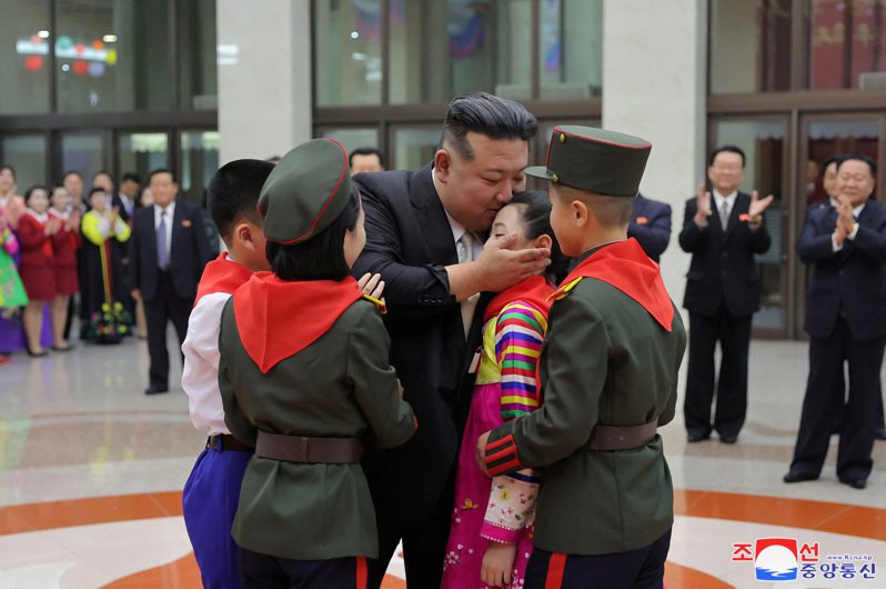 北韓領導人金正恩（中）1日在平壤參加與學生一起慶祝新年的活動。小朋友上台獻花，金正恩回抱小朋友，還親了幾下。（朝中社）