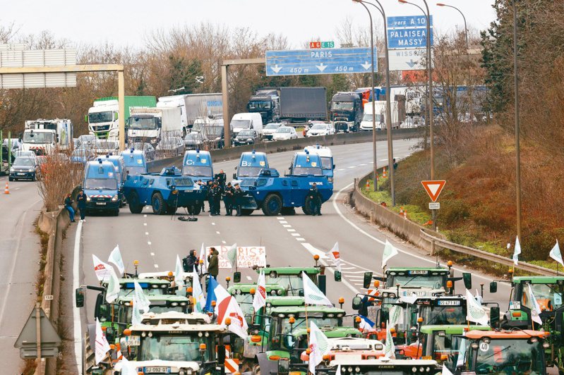 法國憲兵隊裝甲車1月31日在巴黎附近的高速公路與抗議農民的牽引機車隊對峙。(路透)