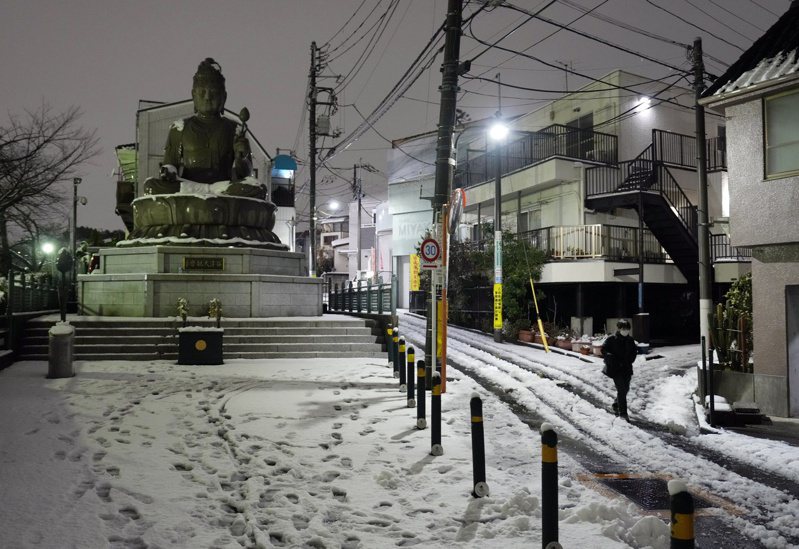 東京大雪釀災，造成上百航班取消、JR列車延誤停駛，路上的交通事也暴增：圖為路人在日本東京積雪覆蓋的街道上行走。（歐新社）