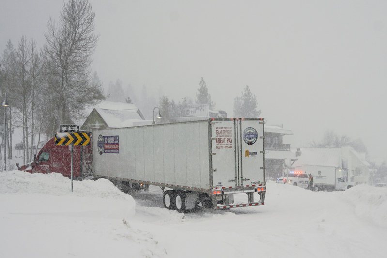 加州和內華達山區遭受暴風雪侵襲，圖為貨櫃車在加州山區冒雪前行。(美聯社)